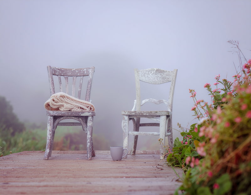 Deux chaises de jardin face à face sur une terrasse, avec deux tasses posées entre elles, invitation à se poser pour discuter