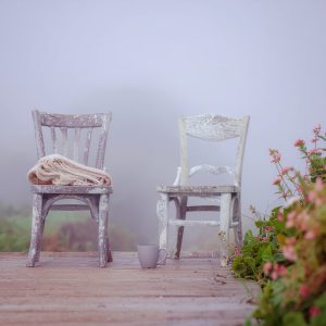 Deux chaises de jardin face à face sur une terrasse, avec deux tasses posées entre elles, invitation à se poser pour discuter