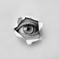 oeil qui apparait dans le trou d'un papier déchiré
